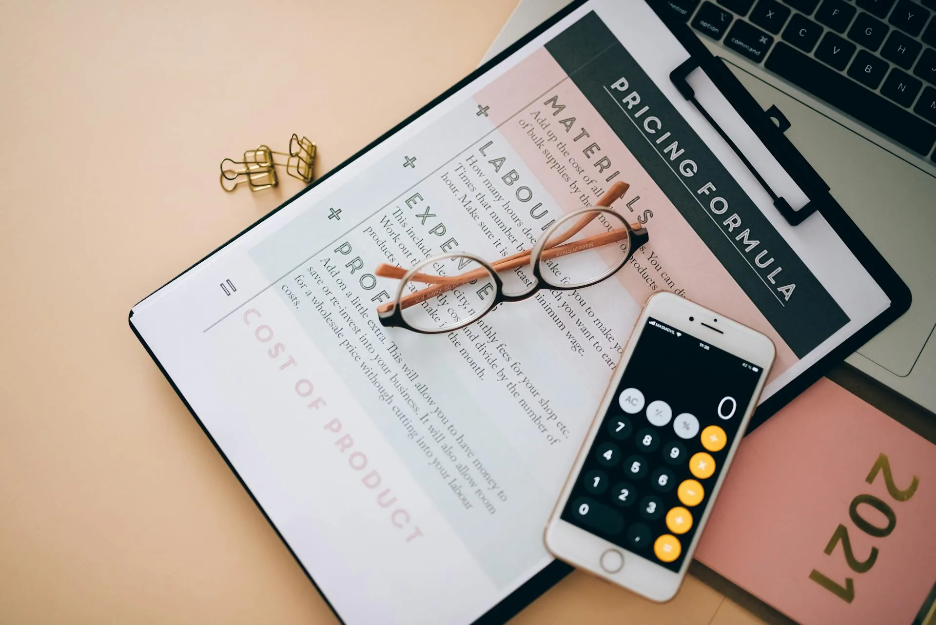 Overhead view of business pricing documents, calculator and eyeglasses on a desk